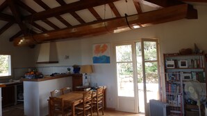 A rustic kitchen with wooden beams, a dining area with chairs, a table, and a view through a glass door to an outdoor garden. - Villa near the sea, beautiful view, two terraces (PIANOTTOLI CALDARELLO)