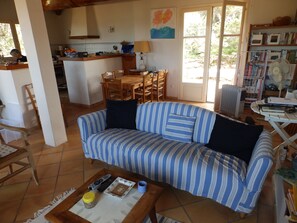 A living room with a striped sofa, a coffee table with remote controls, a book, and a lamp.