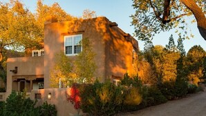 A modern building with a unique architectural design, featuring a prominent window and surrounded by lush greenery. - Light Filled, Spacious Casita~Walk to Downtown & Mountain Views (Santa Fe)