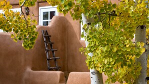 A tree with yellow leaves in front of a building with a window and a ladder leaning against a wall. - Light Filled, Spacious Casita~Walk to Downtown & Mountain Views (Santa Fe)