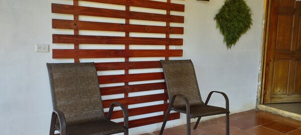 Dos sillas con asientos y respaldos tejidos, frente a un muro de listones de madera.