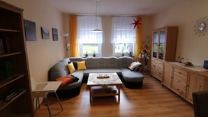 Uma sala de estar com sofá seccional, mesa de centro, estante e armário.