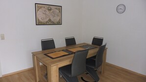 Ein Konferenzraum mit einem Holztisch, vier schwarzen Stühlen, einer Uhr an der Wand und einer Weltkarte als Wandbild.
