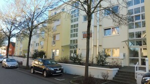 Ein mehrgeschossiges Wohngebäude mit Parkplatz davor.