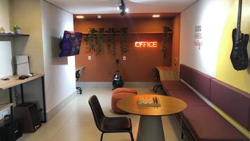 A modern office space with a round table, chairs, a guitar, and an 'OFFICE' sign on the wall.