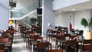 A spacious indoor dining area with multiple tables and chairs, a staircase, and potted plants. - Sleep Inn Paulinia (Paulinia)