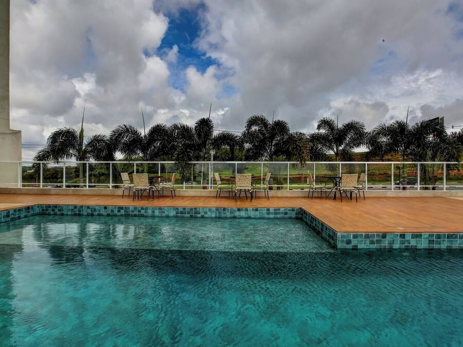 A clear blue pool with tiled edges, surrounded by lounge chairs and palm trees.