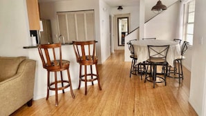 A modern kitchen with wooden flooring, a dining area with a round table and chairs, and a staircase leading to another level. - AMAZING RATES & RAVE REVIEWS! Stunning private pool! 3min walk to the Beach 🏖 (Fort Myers Beach)