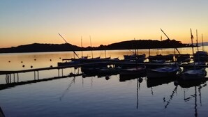 Una marina con barcos amarrados, agua tranquila y cielo despejado.