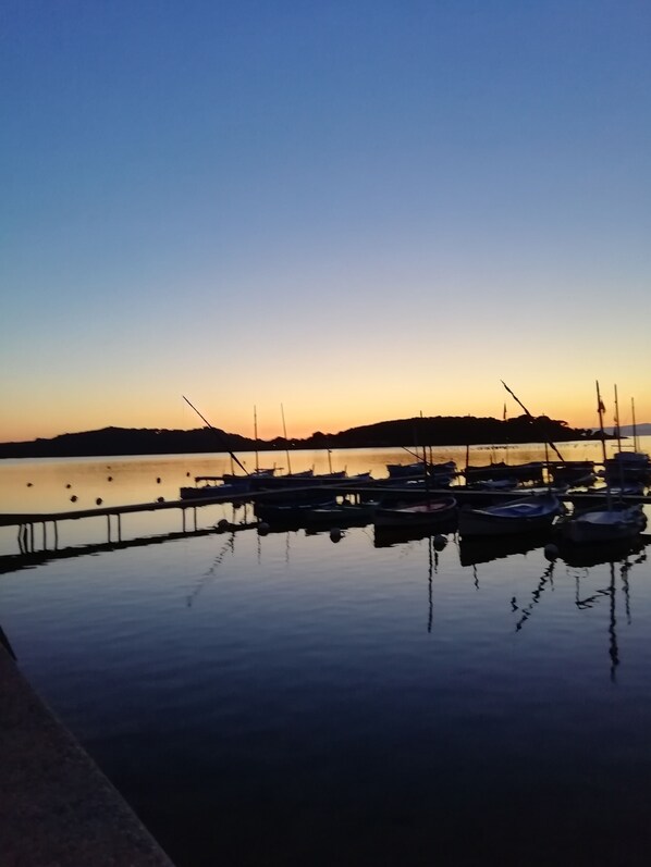 A marina with boats docked, calm water, and a clear sky.
