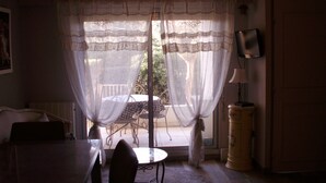 Una habitación con una mesa de comedor, sillas, un televisor en la pared y una ventana con cortinas translúcidas.