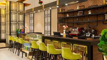 A modern bar area with a long counter, multiple bar stools, and a variety of bar equipment.
