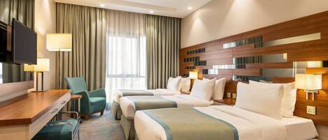 A hotel room with two beds, a desk, a chair, and a television.