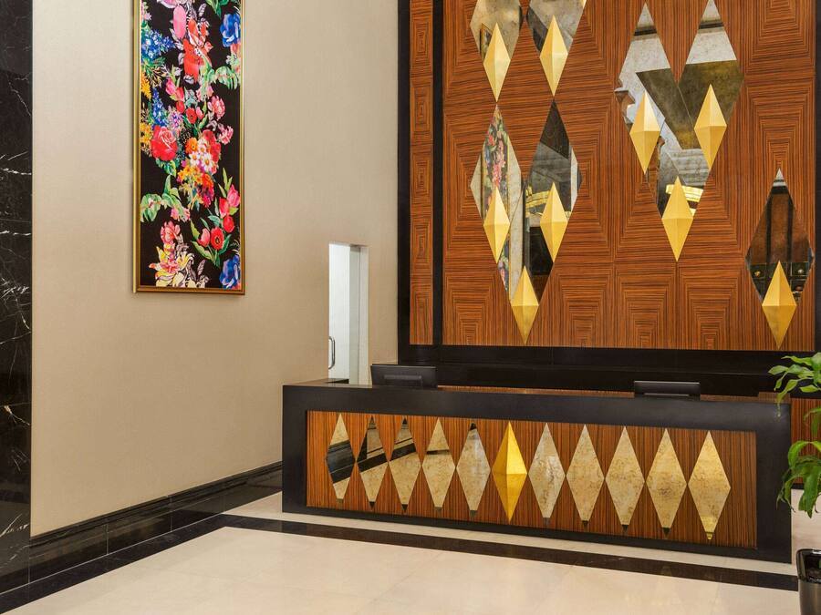 Un área de recepción con diseño de paneles de madera, una obra de arte floral en la pared y una planta en maceta.