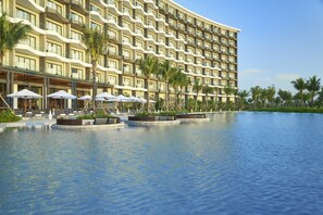A hotel with a large pool area, multiple balconies, and outdoor seating with umbrellas. - Mövenpick Villas & Residences  Phu Quoc (Phu Quoc)