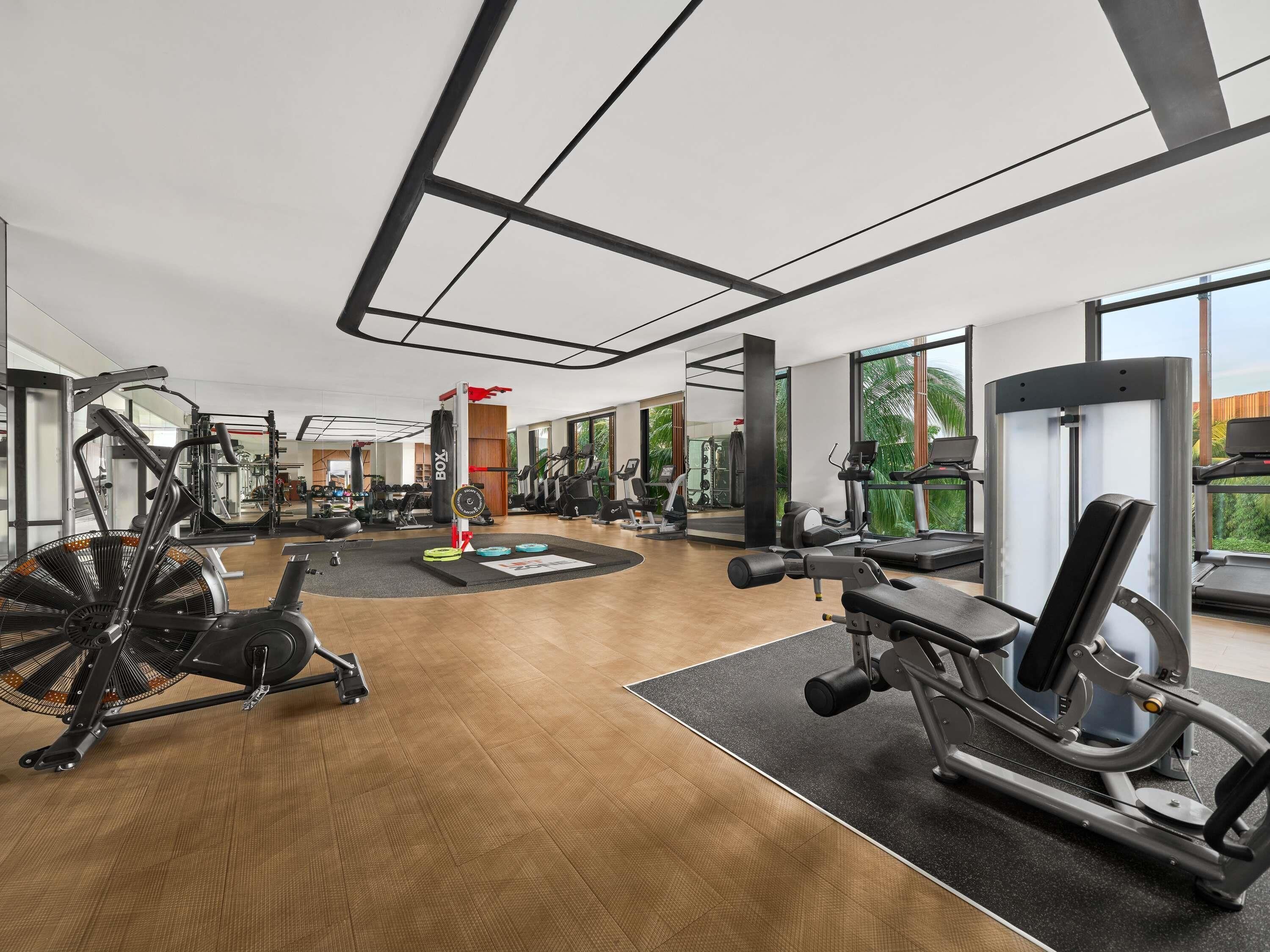 Een moderne sportschool met cardioapparaten, gewichthefapparatuur en een grote spiegel.