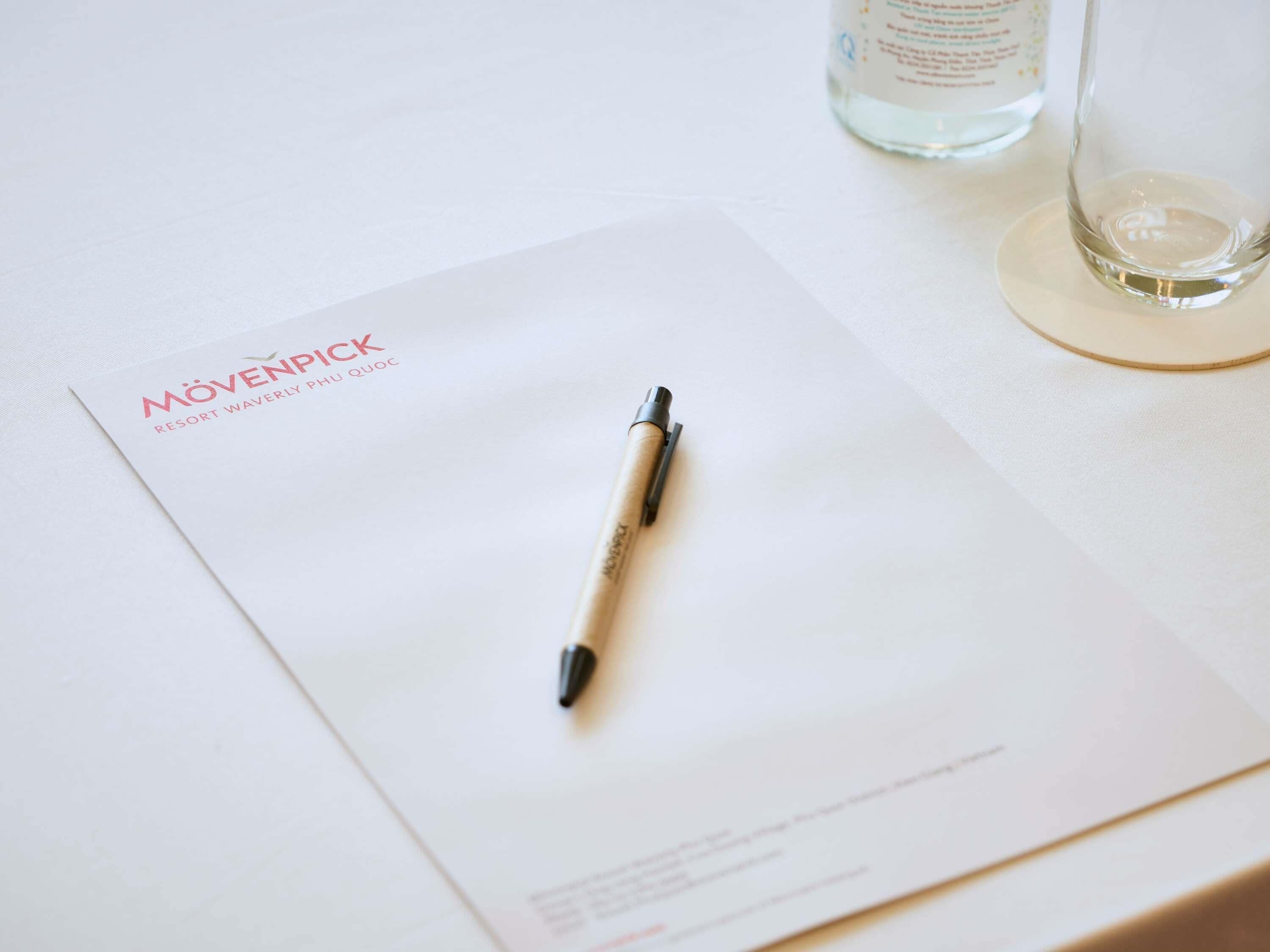 Um documento branco com o título 'MÖVENPICK RESORT WAVERLY PU QUOC' e uma caneta em cima.