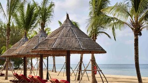 A beach with thatched umbrellas and wooden lounge chairs. - Mövenpick Villas & Residences  Phu Quoc (Phu Quoc)