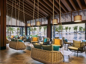 A spacious indoor area with wicker furniture, large windows, and a view of the ocean. - Mövenpick Villas & Residences Phu Quoc (Phu Quoc)