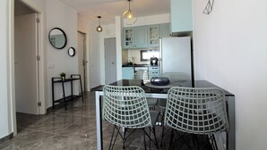 Une cuisine moderne avec un coin repas, comprenant un plan de travail noir, deux chaises et une table ronde.