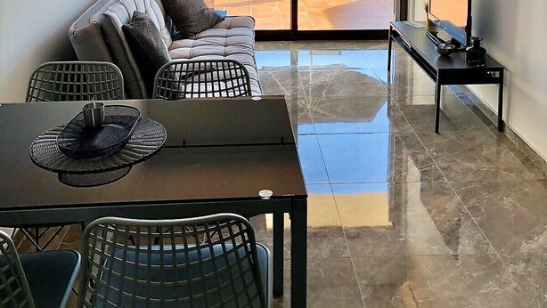 Un salon moderne comprenant un canapé, une table à manger, des chaises et un téléviseur.