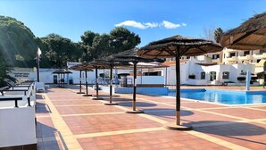 Un espace aménagé au bord de la piscine, doté d’un sol carrelé, de parasols et d’une piscine.
