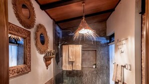 Un baño pequeño con tocador de madera, un espejo grande y una lámpara colgante.