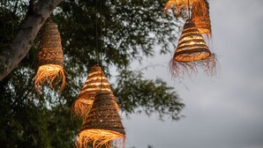Tres lámparas colgantes tejidas sobre un fondo de árboles.