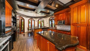 A spacious kitchen with wooden cabinets, granite countertops, and a large island.