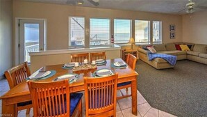 Un área de comedor con una mesa y sillas de madera, un sofá y una ventana con persianas.