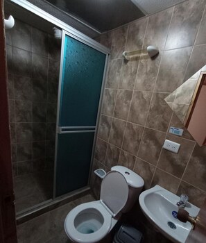 Une salle de bain équipée d’une douche, de toilettes, d’un bidet et d’un lavabo.
