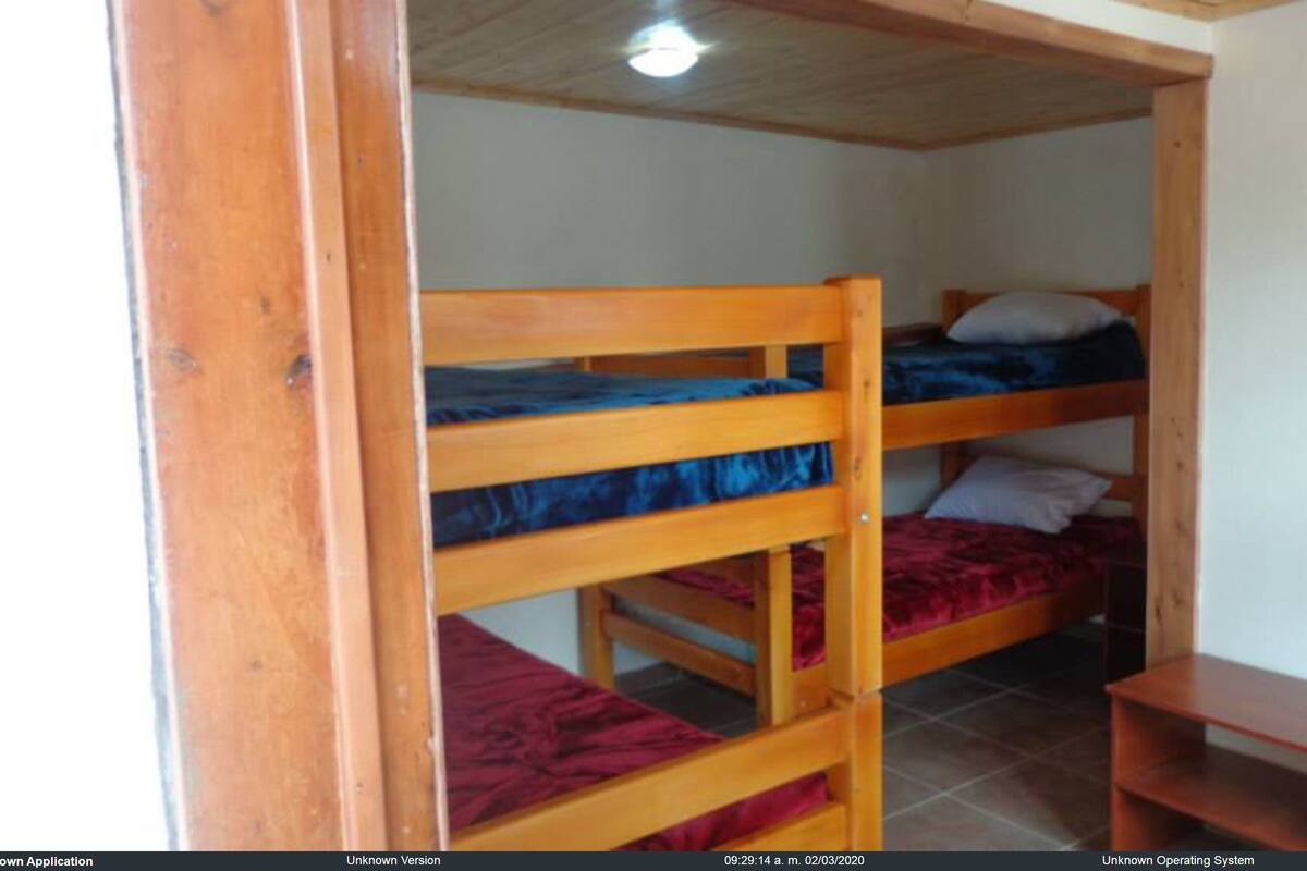 Een kamer met twee stapelbedden, een klein houten tafeltje en een betegelde vloer.