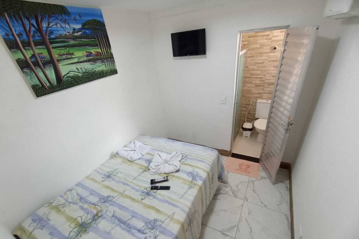 Une petite chambre à coucher, de taille réduite, comprenant un lit, un téléviseur et une salle de bain.