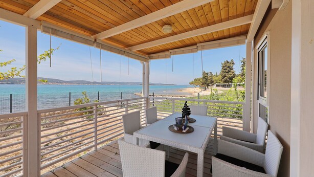 A covered outdoor seating area with a view of the beach and sea.