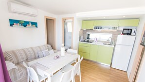 A modern kitchen with green cabinets, a white refrigerator, and a microwave.