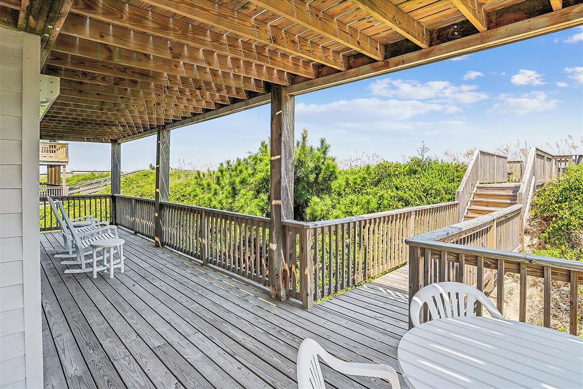 A wooden deck with outdoor seating and a view of greenery.