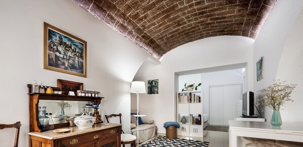 Un salón espacioso con un aparador de madera, un sofá, una zona de comedor con televisor y una estantería.