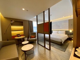 Una habitación de hotel moderna con una cama, un escritorio, una silla y un sofá.