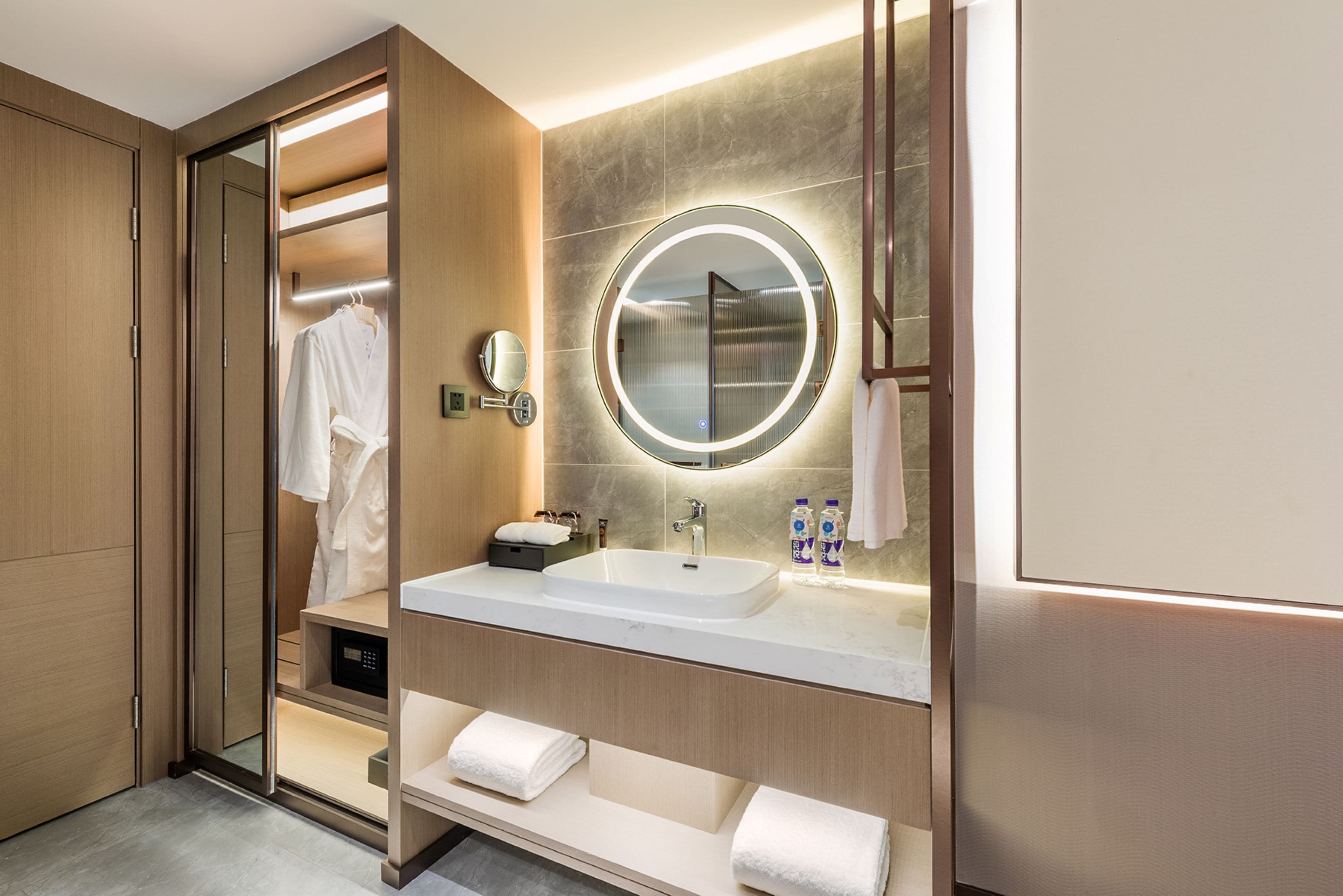 A modern bathroom with a walk-in closet, a large mirror, a sink, and a towel rack.