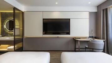 Una habitación de hotel moderna con un televisor de pantalla plana grande, una mesita de noche, una silla y una cama.