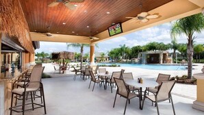 Eine Außenpatio-Terrasse mit Holzboden, Deckenventilatoren und einem Pool im Hintergrund.