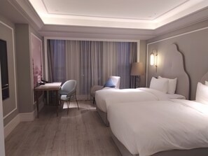 Una habitación de hotel con dos camas, un escritorio, una silla, un televisor y una ventana con cortinas.