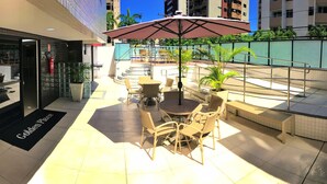 An outdoor seating area with tables and chairs, a fire extinguisher, and a sign reading "Golden Place". - Vacanze - Golden Place 503 (Maceió)