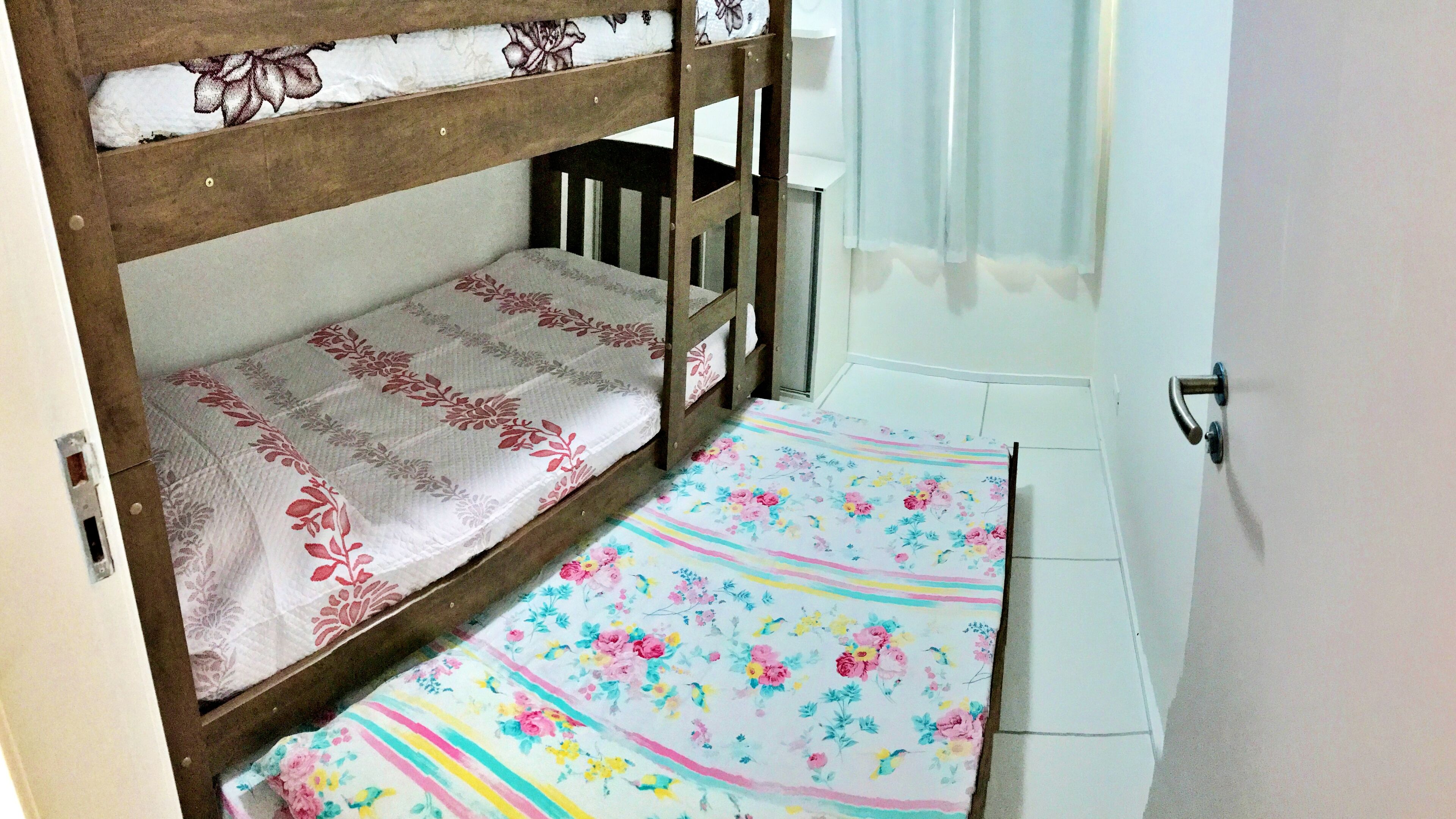 Una cama litera con ropa de cama floral y un tapete a rayas al pie de la cama.