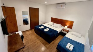 Een hotelkamer met twee bedden, een houten bureau, een spiegel en een plafondventilator.