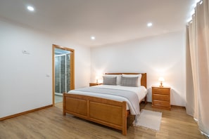 A bedroom with a wooden bed, bedside tables, a mirror, and a view of a stone wall.