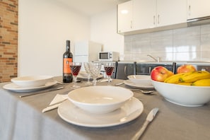 A modern kitchen with white cabinets, a microwave, and a fruit bowl on the counter.