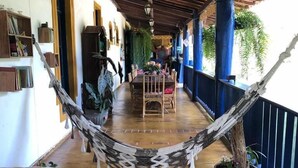 Un espacio al aire libre techado con una hamaca, una mesa de comedor con sillas y un sofá.
