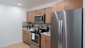 A modern kitchen with stainless steel appliances, wooden cabinets, and a tiled backsplash. - Stay Alfred at Riverfront Park (Spokane)
