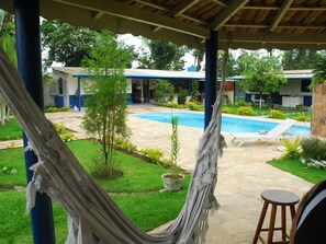 Zona de piscina con una hamaca, una silla de descanso y un taburete de bar.